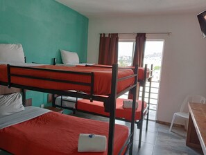 Un dormitorio con literas, un escritorio y una ventana con cortinas.