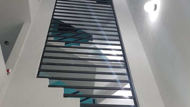 Una escalera moderna con un diseño geométrico en los peldaños y barandilla negra.