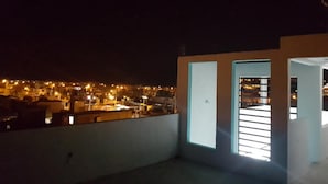 Una terraza en la azotea con vistas a la ciudad de noche.