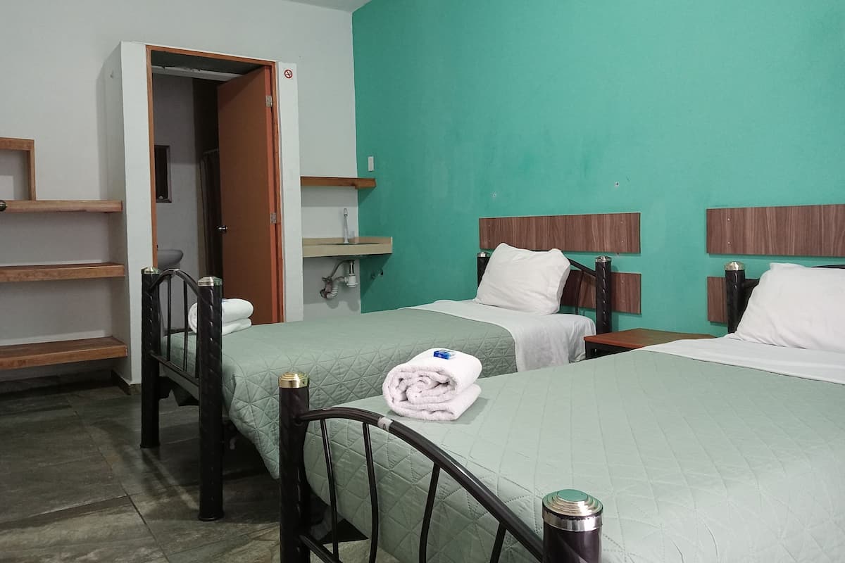 A hotel room with two beds, a sink, and a door leading to a bathroom.