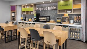 A modern cafe with an 'inspired table' sign, a 'good morning' greeting, and a variety of seating options including tables and chairs. - Home2 Suites by Hilton Las Cruces (Las Cruces)