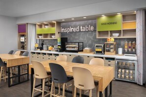 A modern cafe with an 'inspired table' sign, a 'good morning' greeting, and a variety of seating options including tables and chairs. - Home2 Suites by Hilton Las Cruces (Las Cruces)