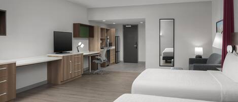 A modern hotel room with a large bed, a desk with a computer, a television, and a kitchenette.