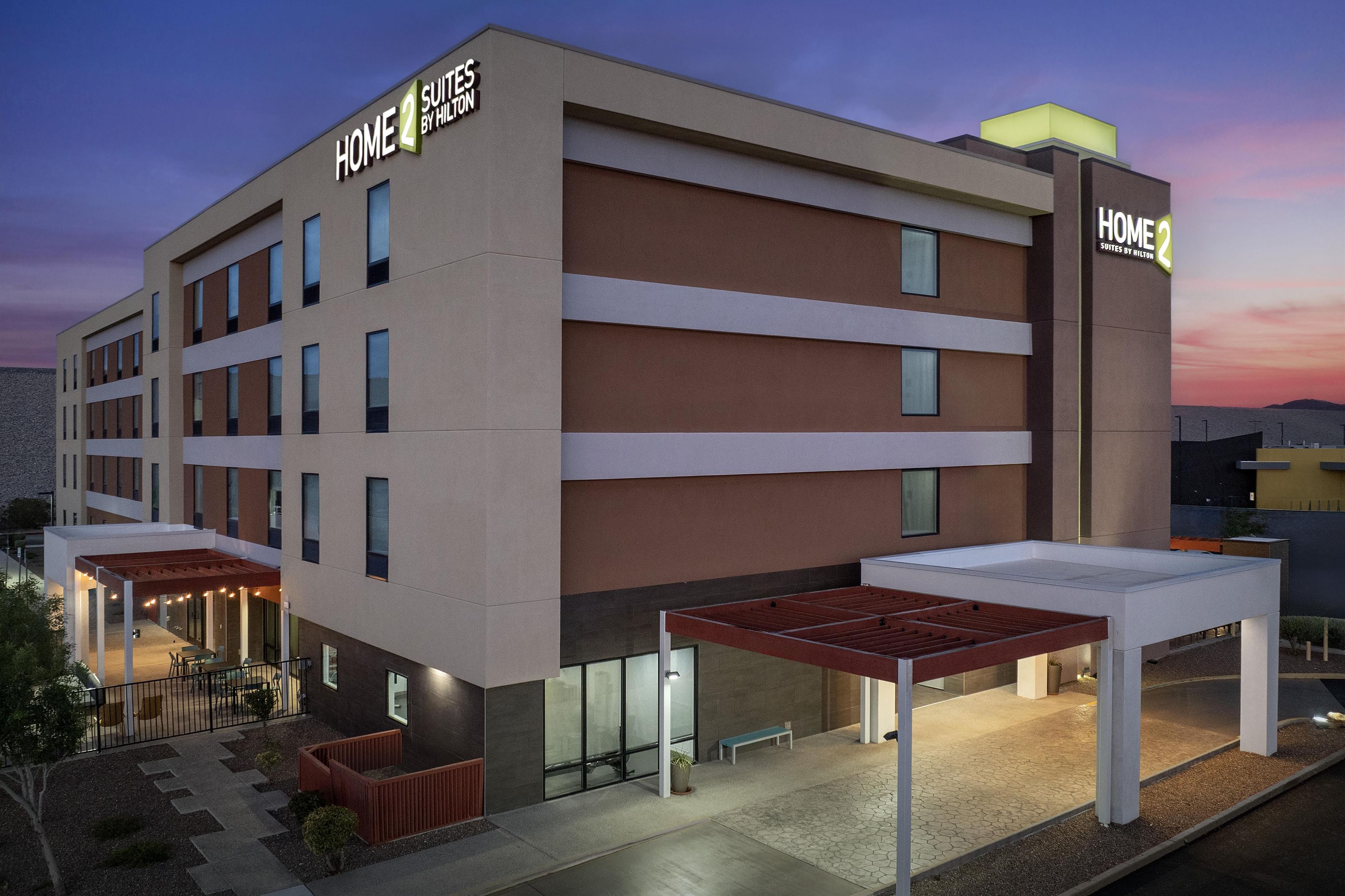 Um hotel moderno com telhado plano, várias janelas e área de estar externa coberta.
