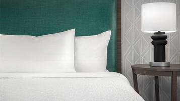 A neatly made bed with white bedding and a green headboard.