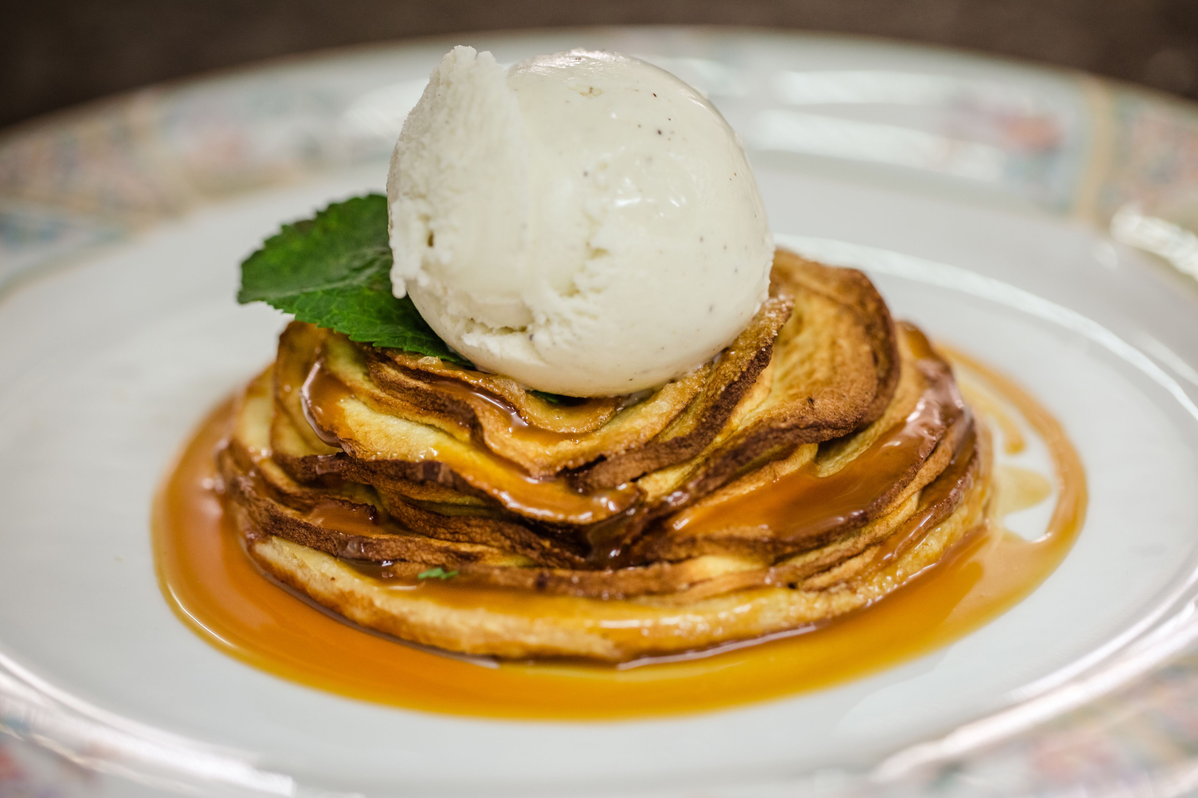 Een stapel pannenkoeken met siroop en een bolletje ijs.