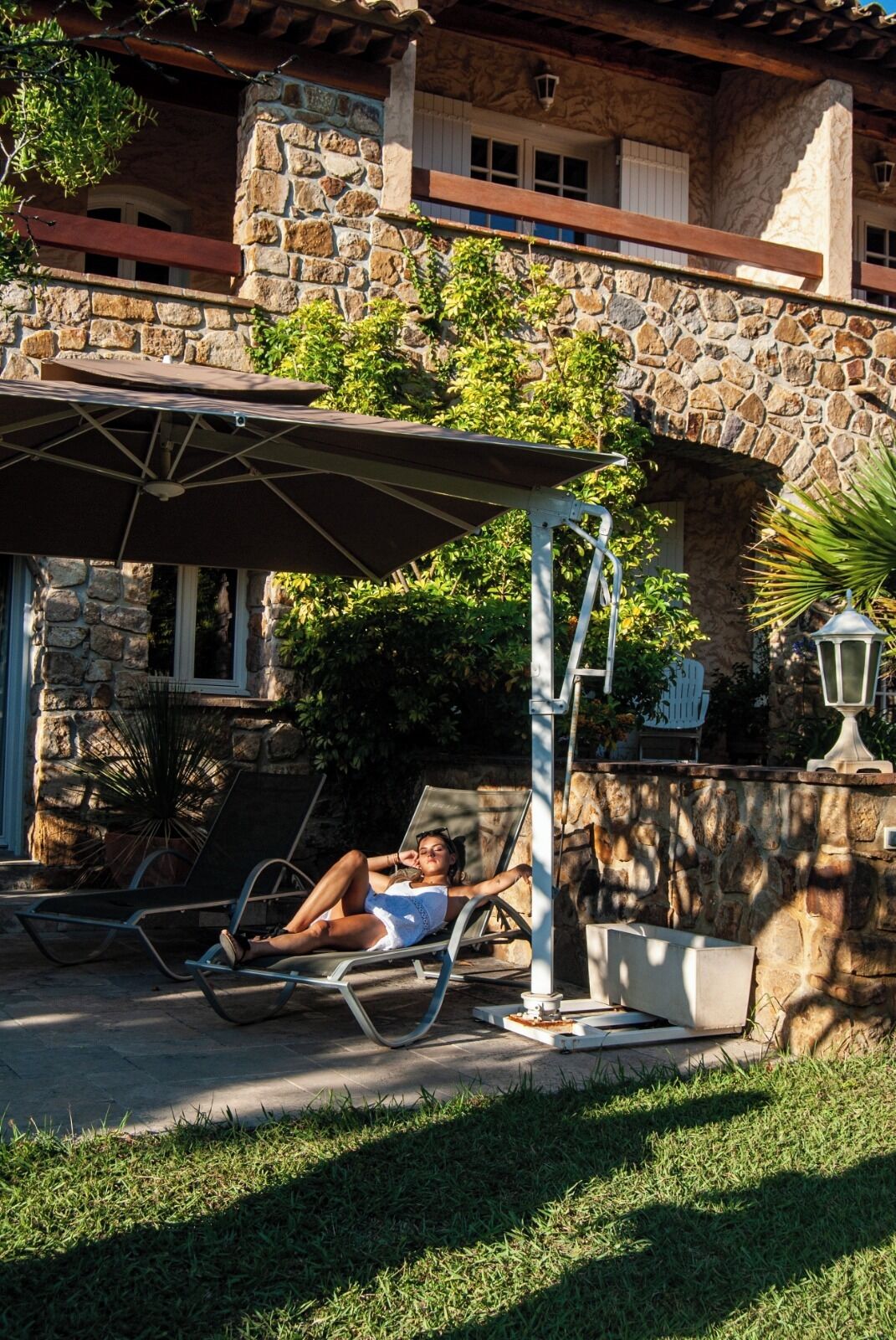 Ein Steinhäuschen mit einer Terrasse, inklusive einer überdachten Sitzgelegenheit mit Tisch und Stühlen.
