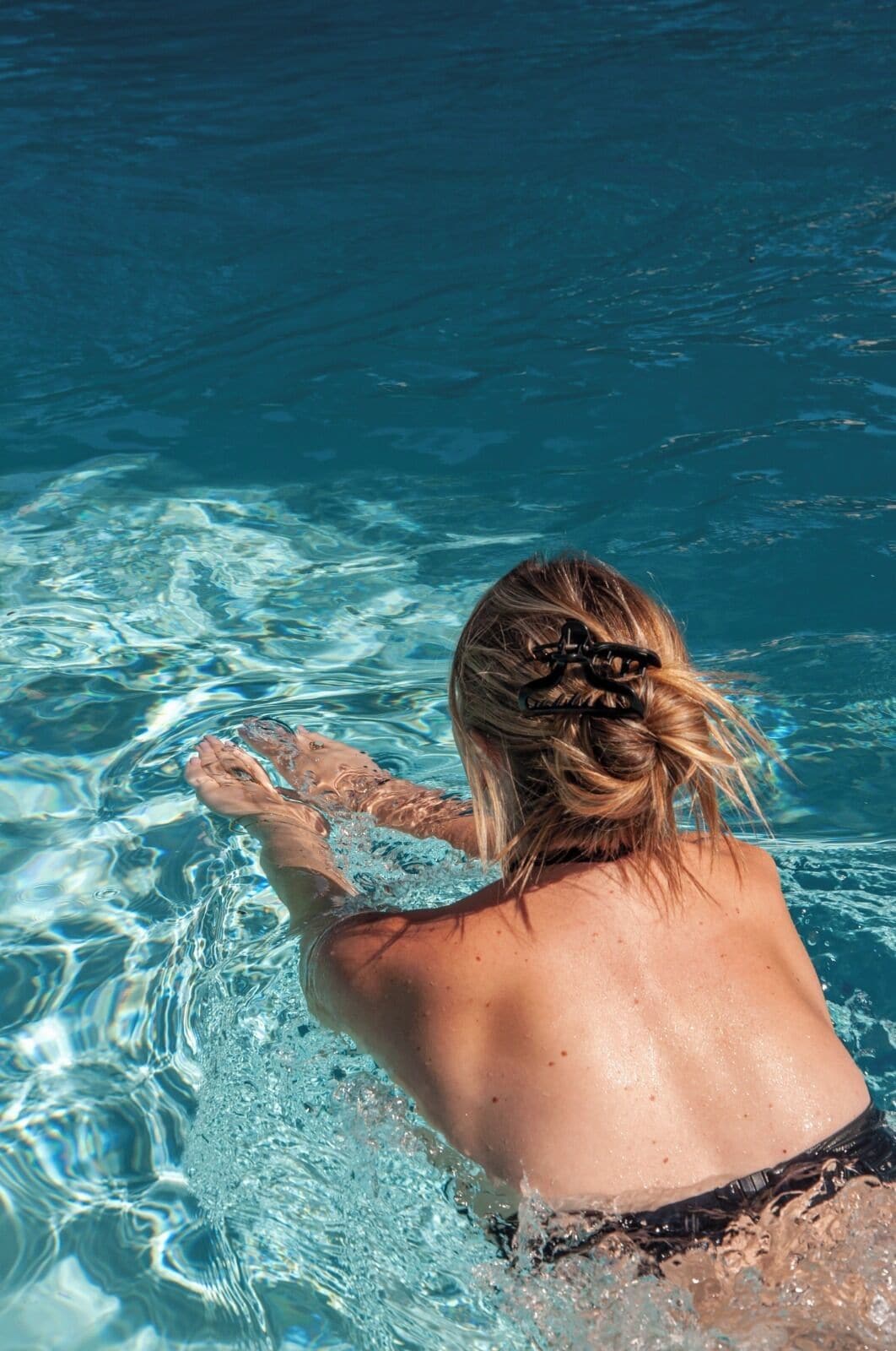 Una persona nadando en una piscina de agua cristalina azul.
