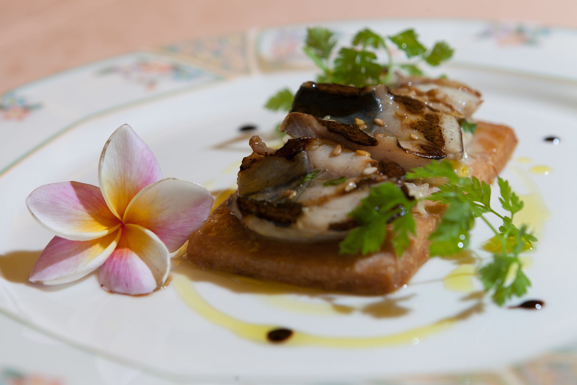 Une assiette avec une tranche de pain grillé garnie de champignons et décorée d’une fleur.