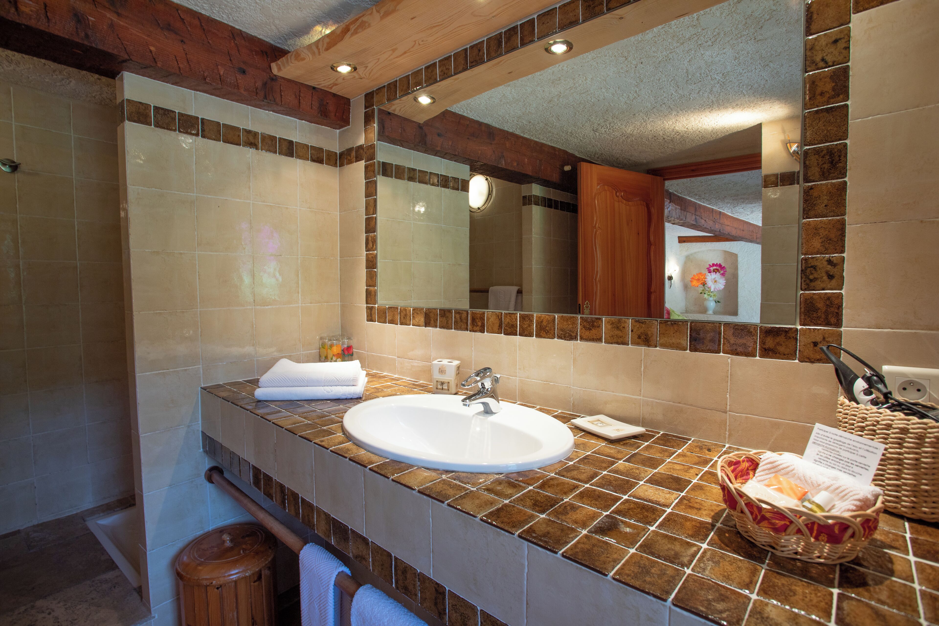 A bathroom with a large mirror, a sink, and a wooden vanity.