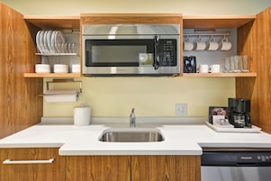 Una cocina con microondas de acero inoxidable, un fregadero y armarios de madera.