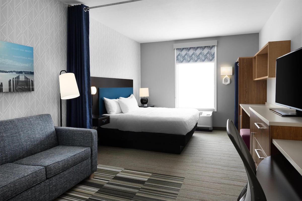 Une chambre d’hôtel moderne équipée d’un lit, d’un canapé, d’un bureau et d’une télévision.