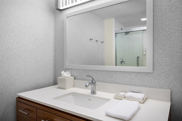 Un baño con un espejo grande, un lavabo, una toalla y una caja de pañuelos.