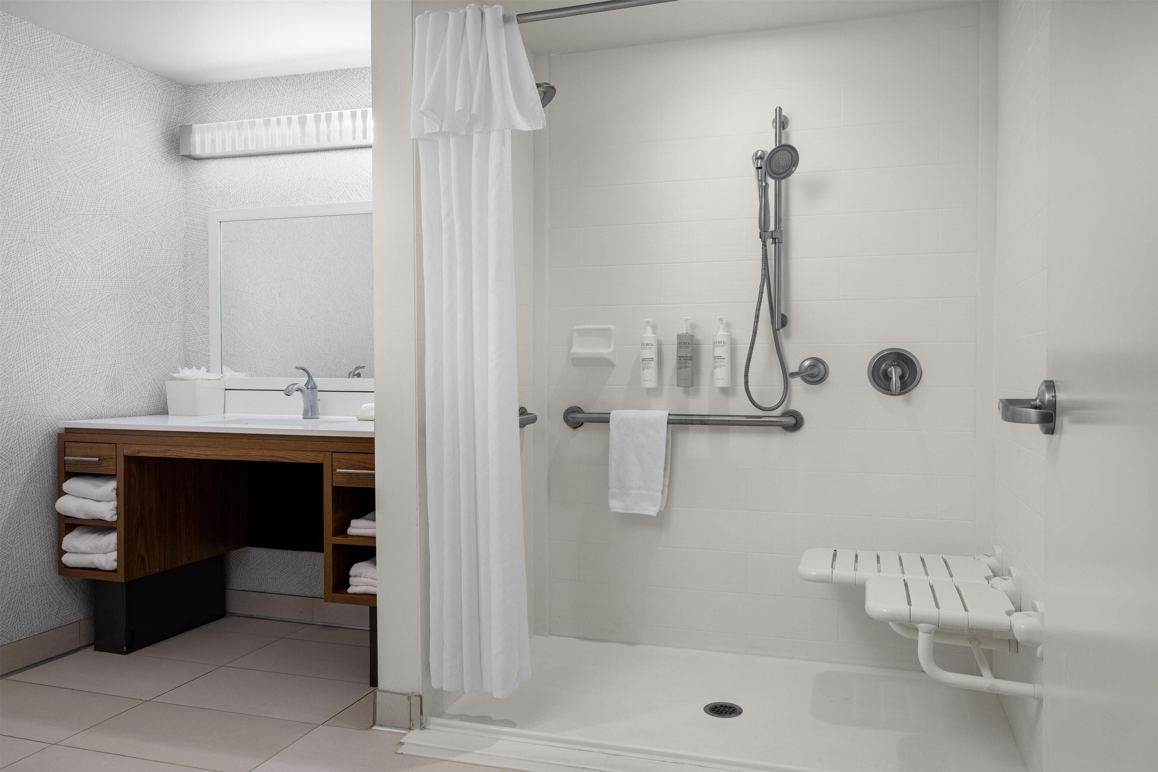 A modern bathroom with a shower, a sink with a wooden vanity, and a white towel rack.