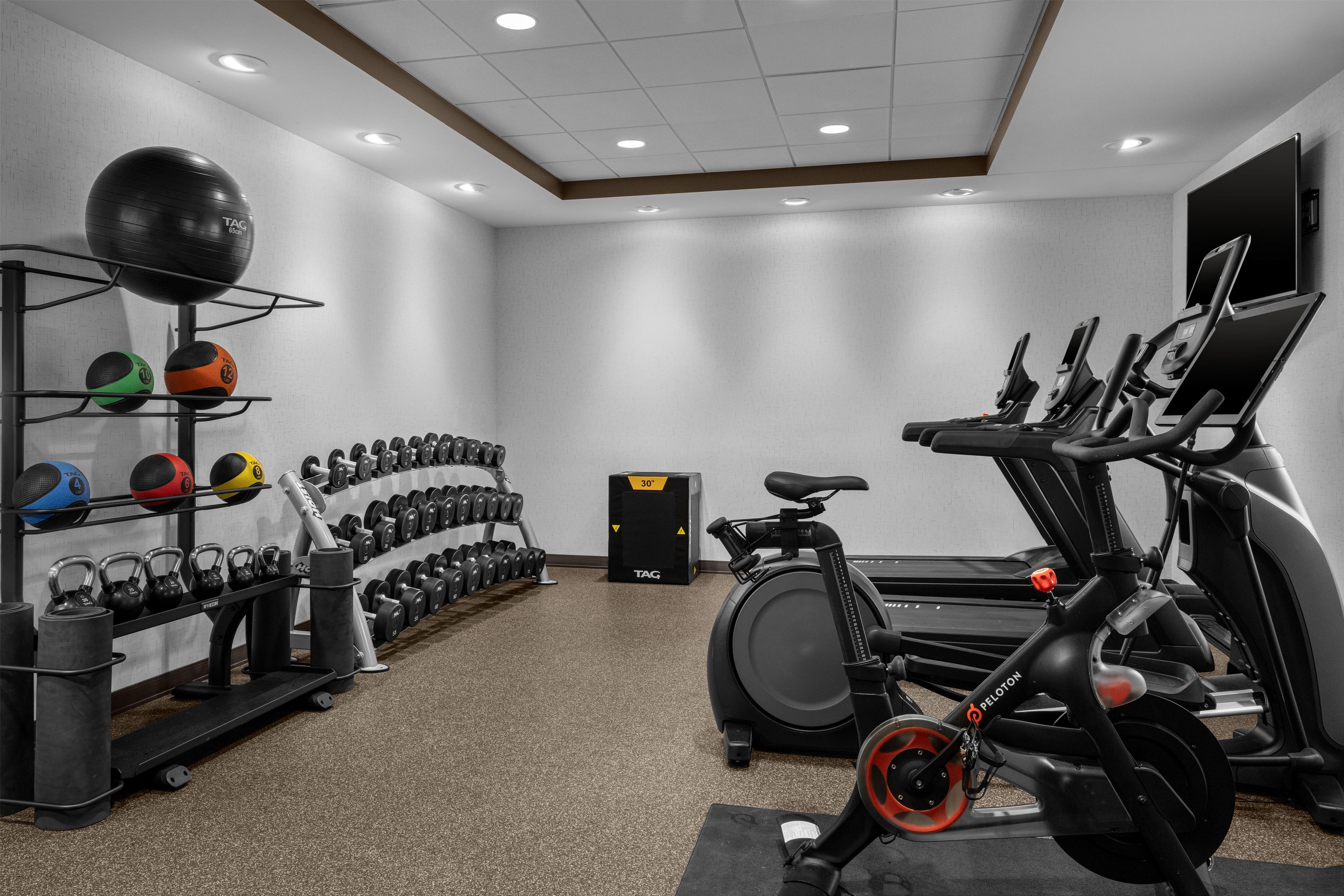 Una palestra con attrezzatura per esercizi, tra cui tapis roulant, cyclette e rastelli per pesi.