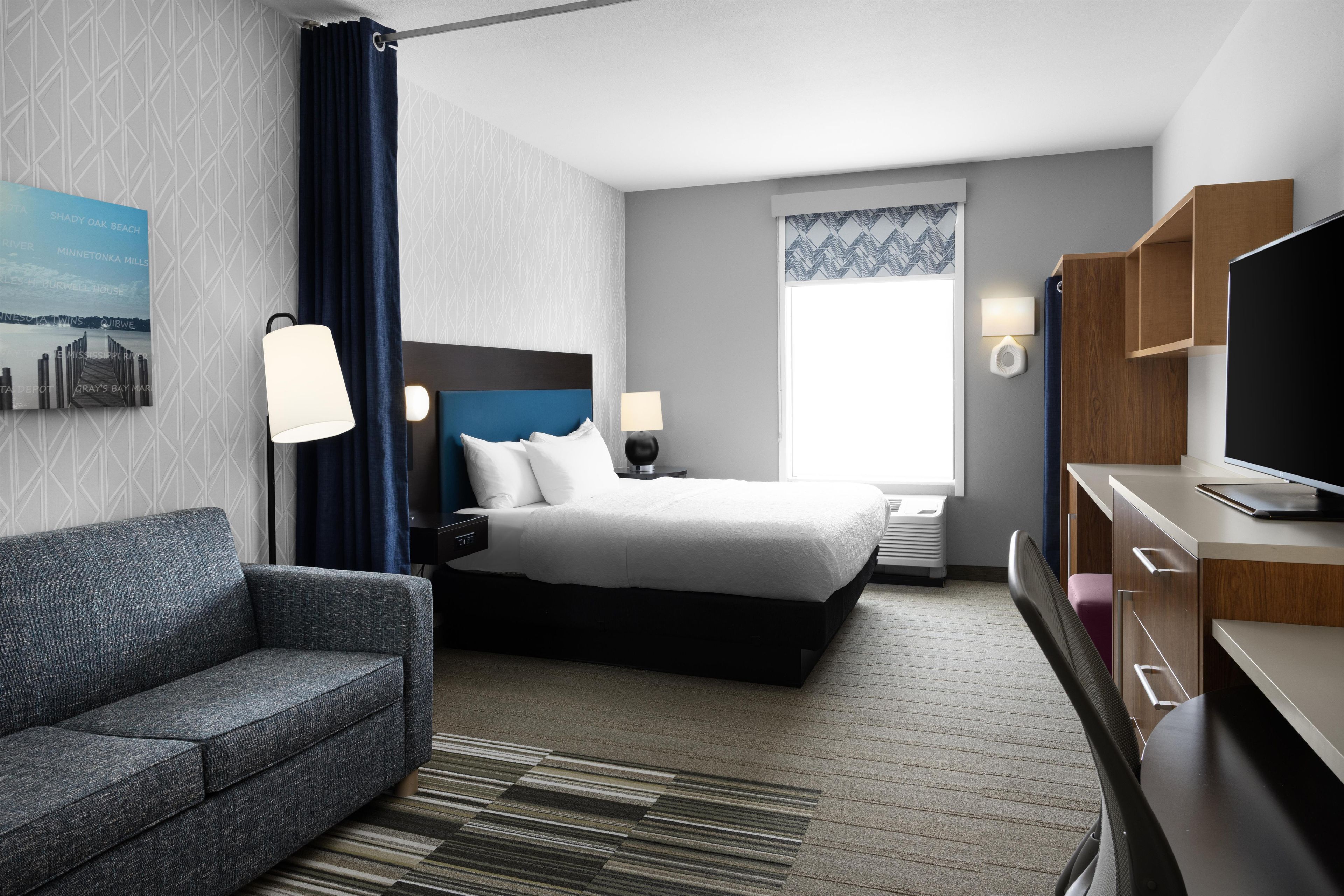 Une chambre d’hôtel avec un lit, un bureau, une télévision et une fenêtre.