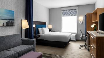 Una habitación de hotel con una cama, un escritorio, una silla, un sofá y un televisor.