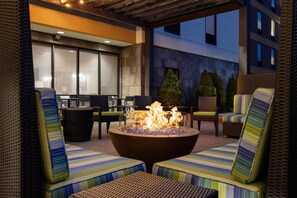 An outdoor seating area with wicker furniture and a central fire feature.