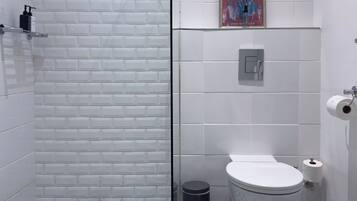 A bathroom with a checkered floor, a glass shower enclosure, a toilet, and a sink.