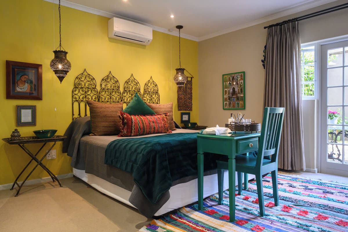 Une chambre à coucher avec un lit, une table, une chaise et un tapis coloré.