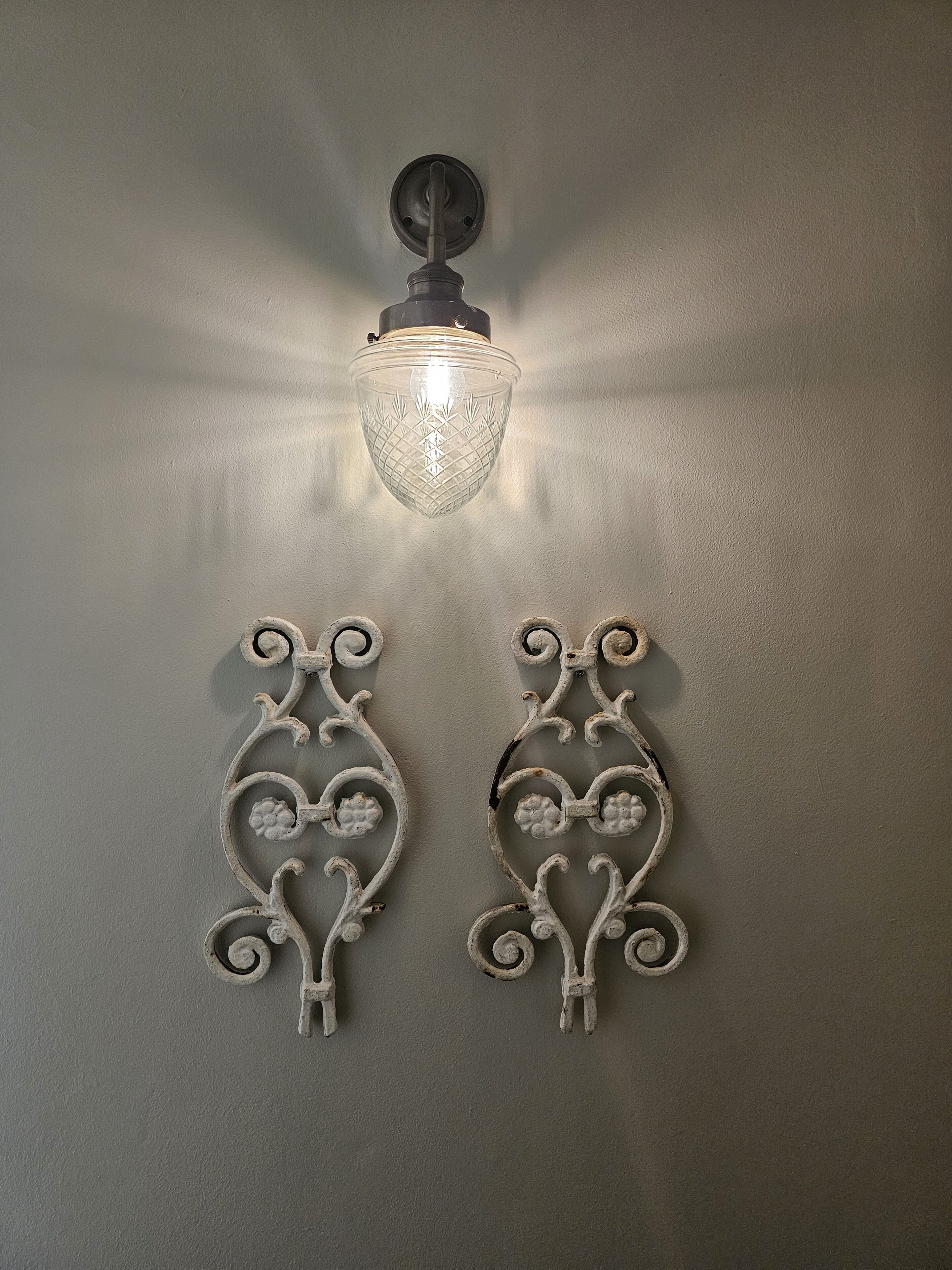 A wall-mounted light fixture with a clear glass shade and two ornate metal sconces.
