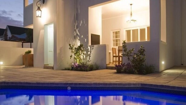 Een modern huis met een zwembad, buitenverlichting en een terras.