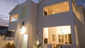 Een modern huis met twee verdiepingen, grote ramen en een helder verlichte ingang.