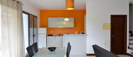 A modern kitchen with white cabinets, a black countertop, and a hanging pendant light.