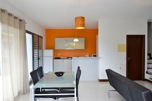 A modern kitchen with white cabinets, a black countertop, and a hanging pendant light. - VILAS ESPÍRITO SANTO by brugrani (Porto Santo)