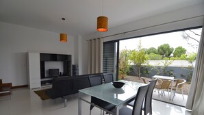 A modern living room with a glass dining table, black chairs, a sofa, and a TV. - VILAS ESPÍRITO SANTO by brugrani (Porto Santo)