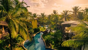 Une piscine entourée de palmiers et un petit bâtiment.