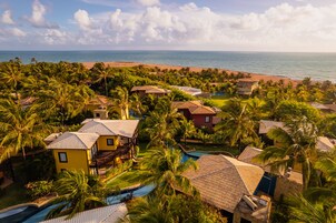 A resort with multiple buildings, a swimming pool, and a beach view.
