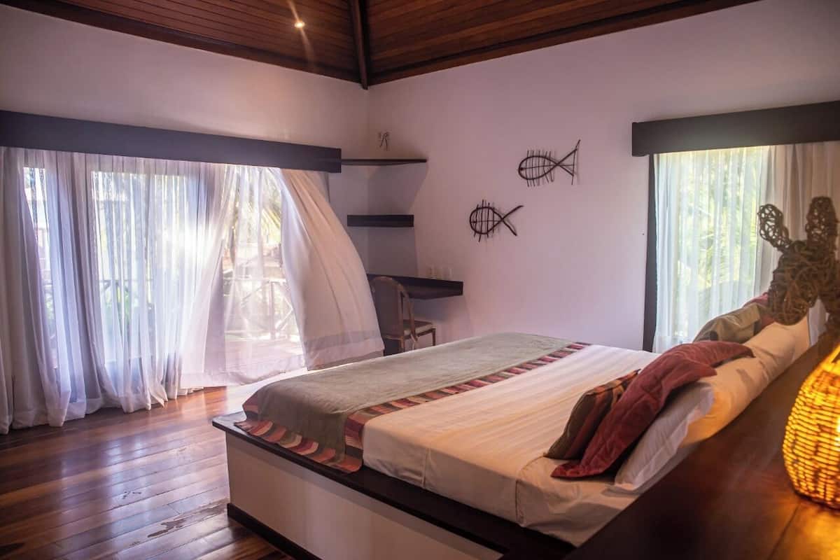 Une chambre à coucher comprenant un lit, un plancher en bois, un bureau et deux décorations murales représentant des poissons.