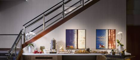 A modern hotel lobby with a staircase, a bar area with a Jackrabbit sign, and two large abstract paintings on the wall.