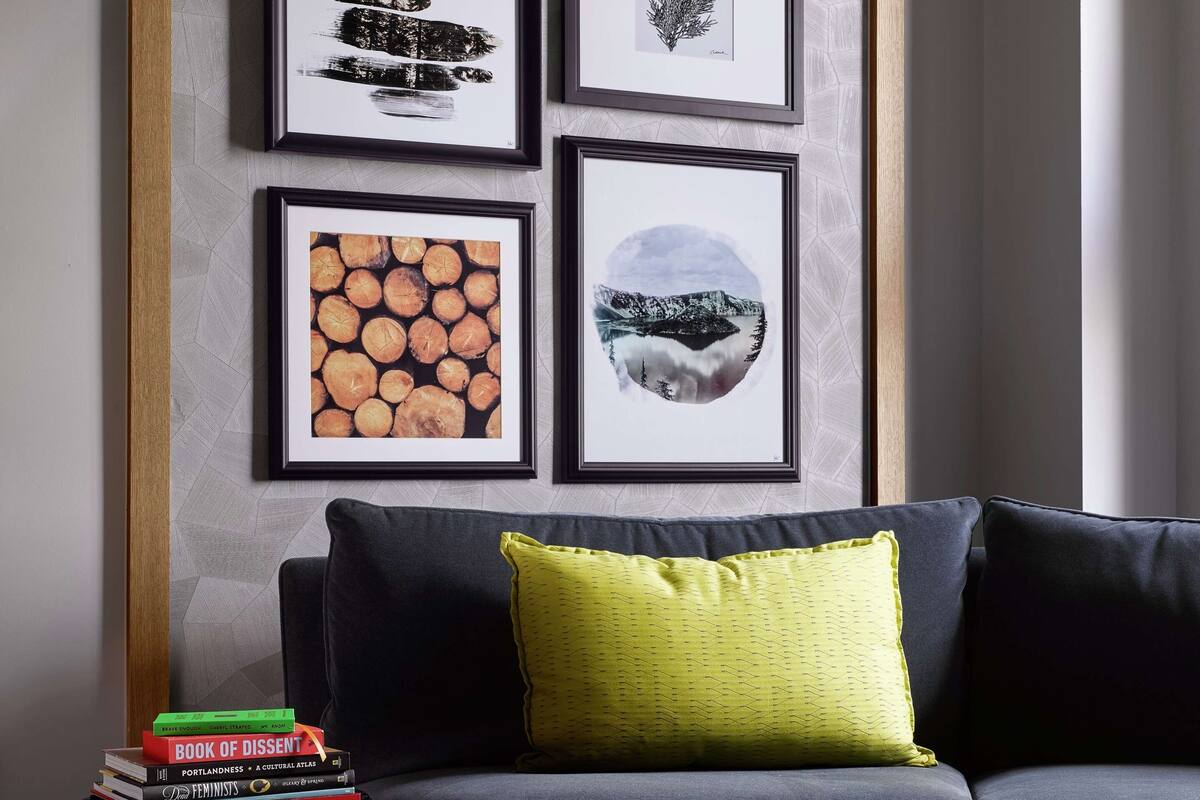 A living room with a dark sofa, a yellow pillow, and a stack of books on a small table.