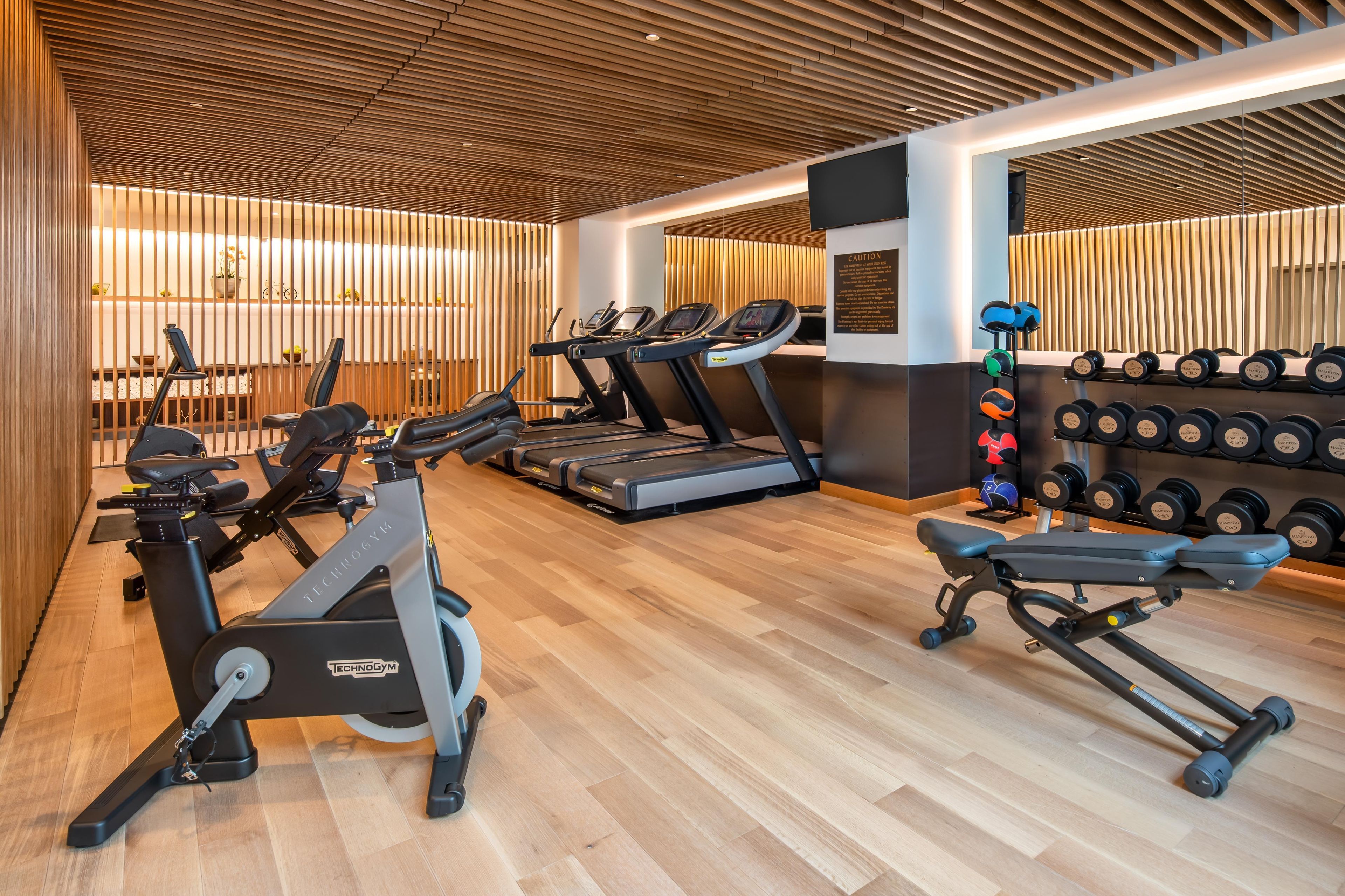 Un gimnasio con cintas de correr, elípticas y una zona de prensa de pesas.