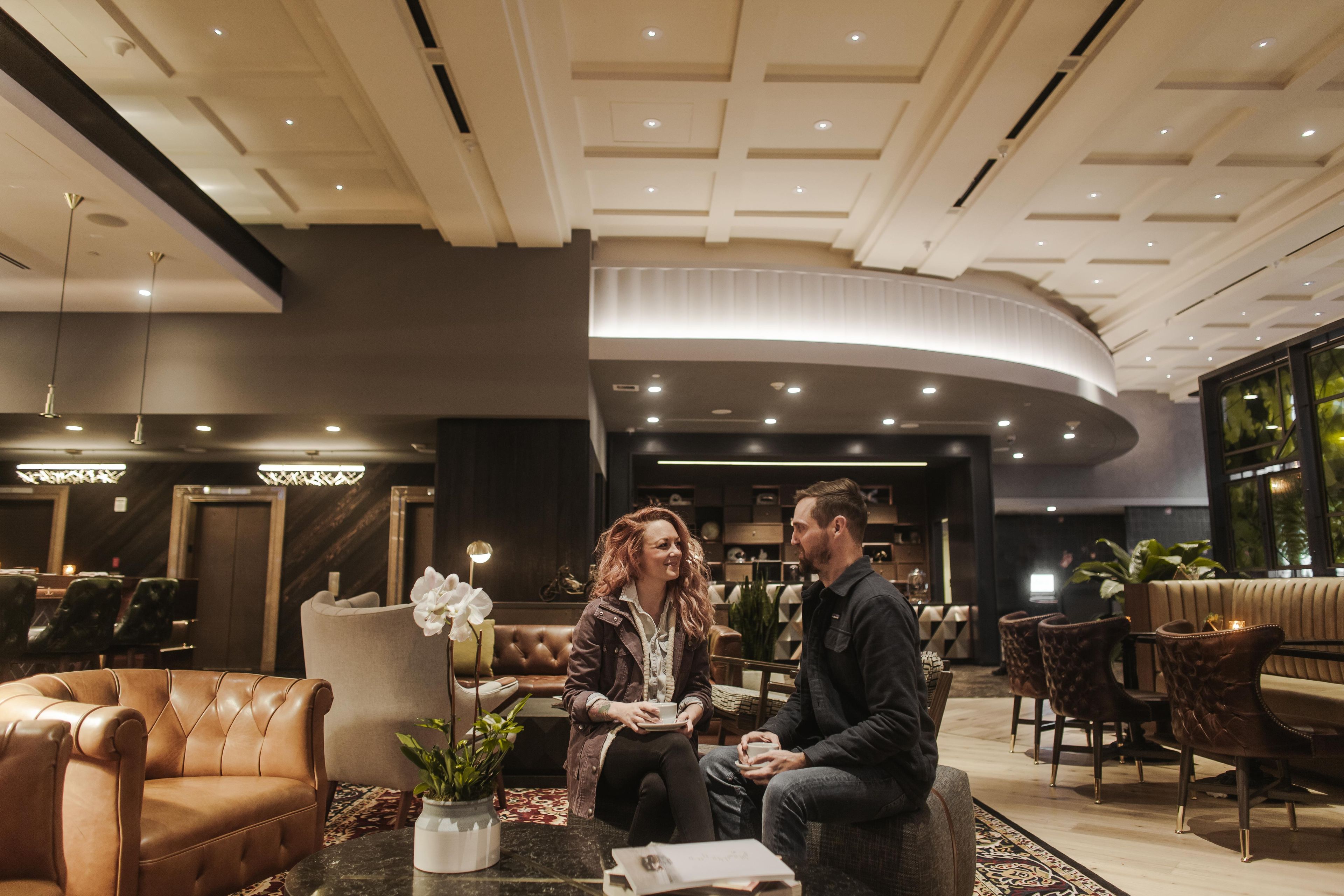 Rebedor d'hotel modern amb seients de pell, una taula de cafè i una planta en test.