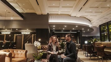 Rebedor d'hotel modern amb seients de pell, una taula de cafè i una planta en test.