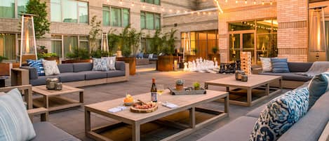 An outdoor seating area with sofas, tables, and a chessboard.