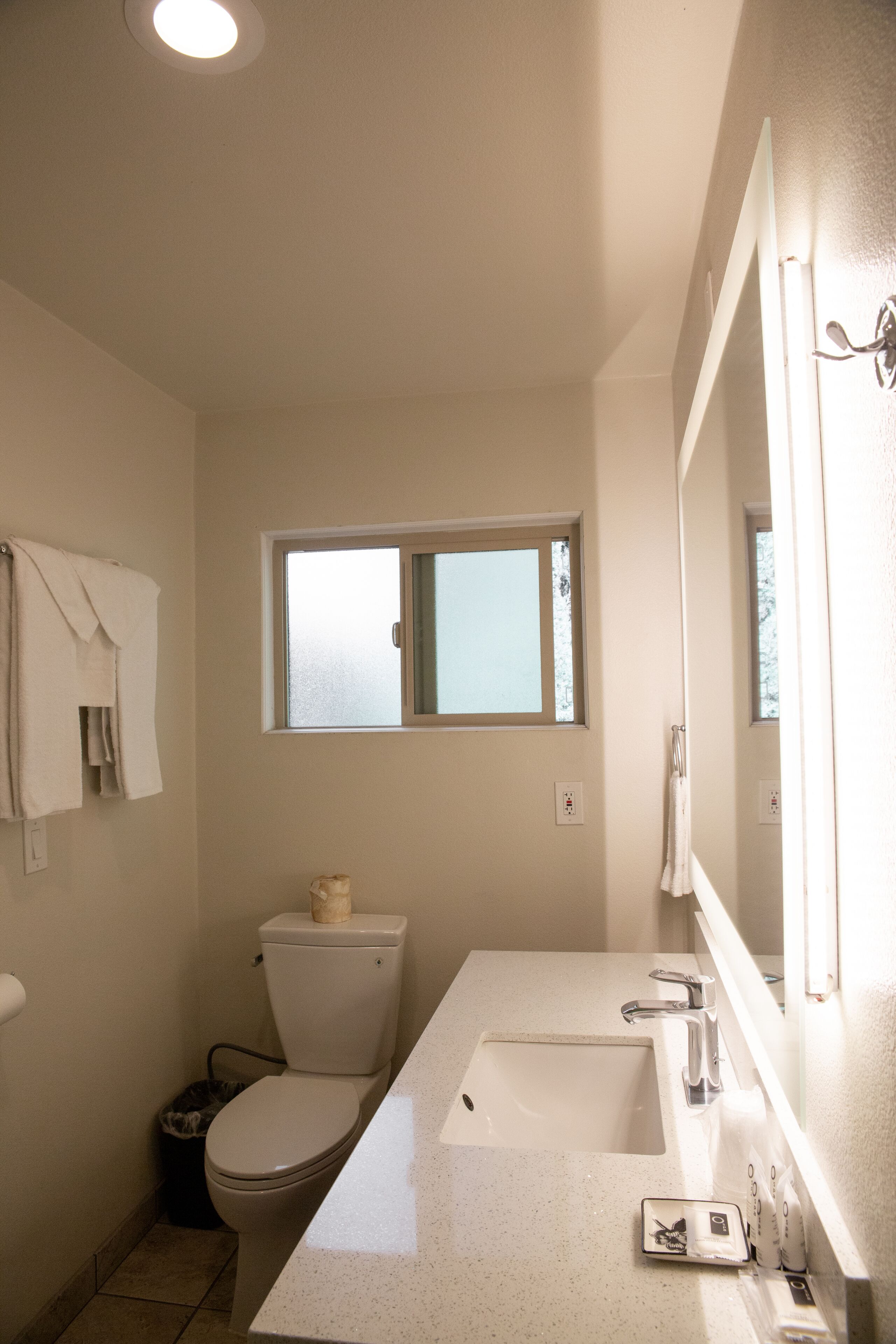 A bathroom with a toilet, sink, and window.