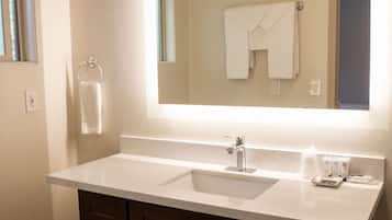 Un baño con lavamanos doble, muebles oscuros, un inodoro y un espejo grande sobre el lavamanos.