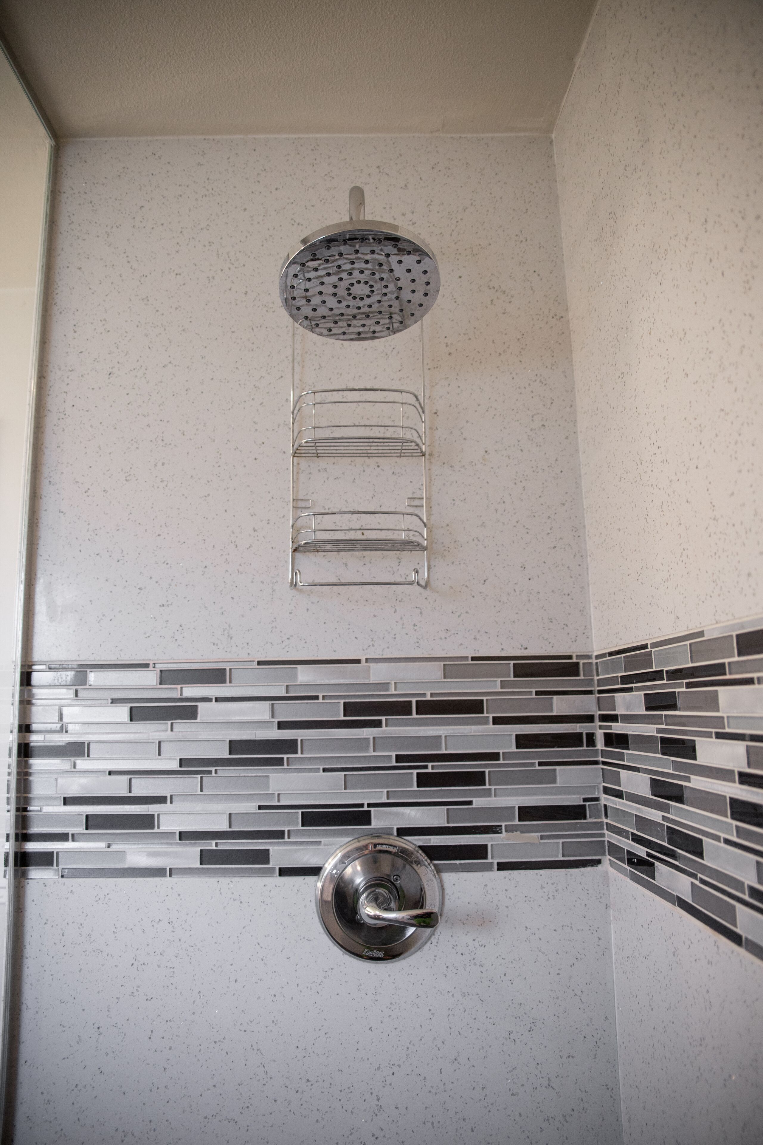 Zona de ducha con ducha de lluvia, toallero de pared y salpicadero de azulejos.