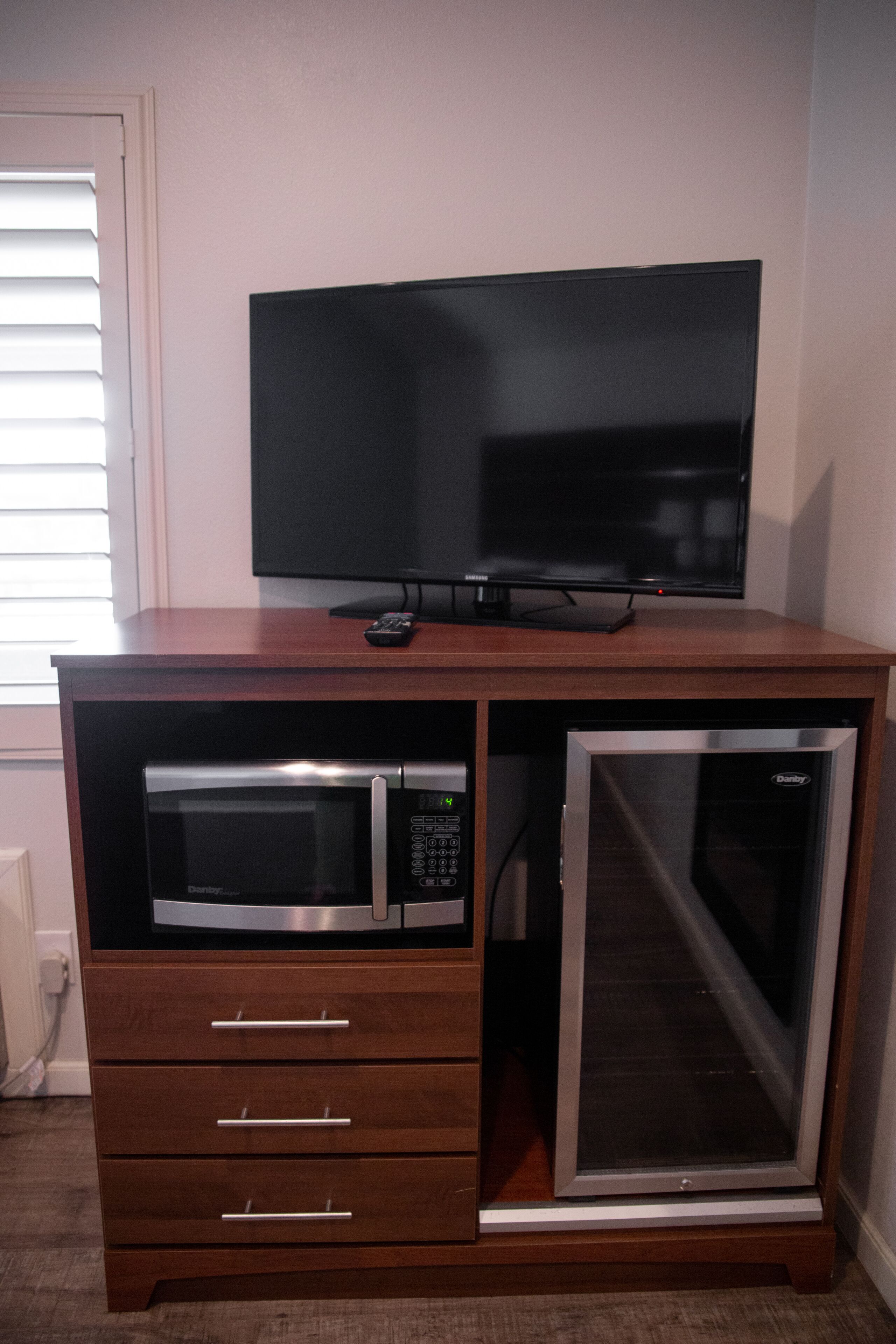A wooden cabinet with a built-in microwave, oven, and a flat-screen TV on top.
