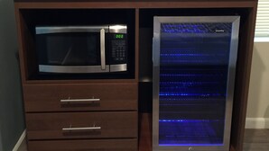 A wooden cabinet with a microwave, a Danby refrigerator, and a Samsung TV displaying a program guide.