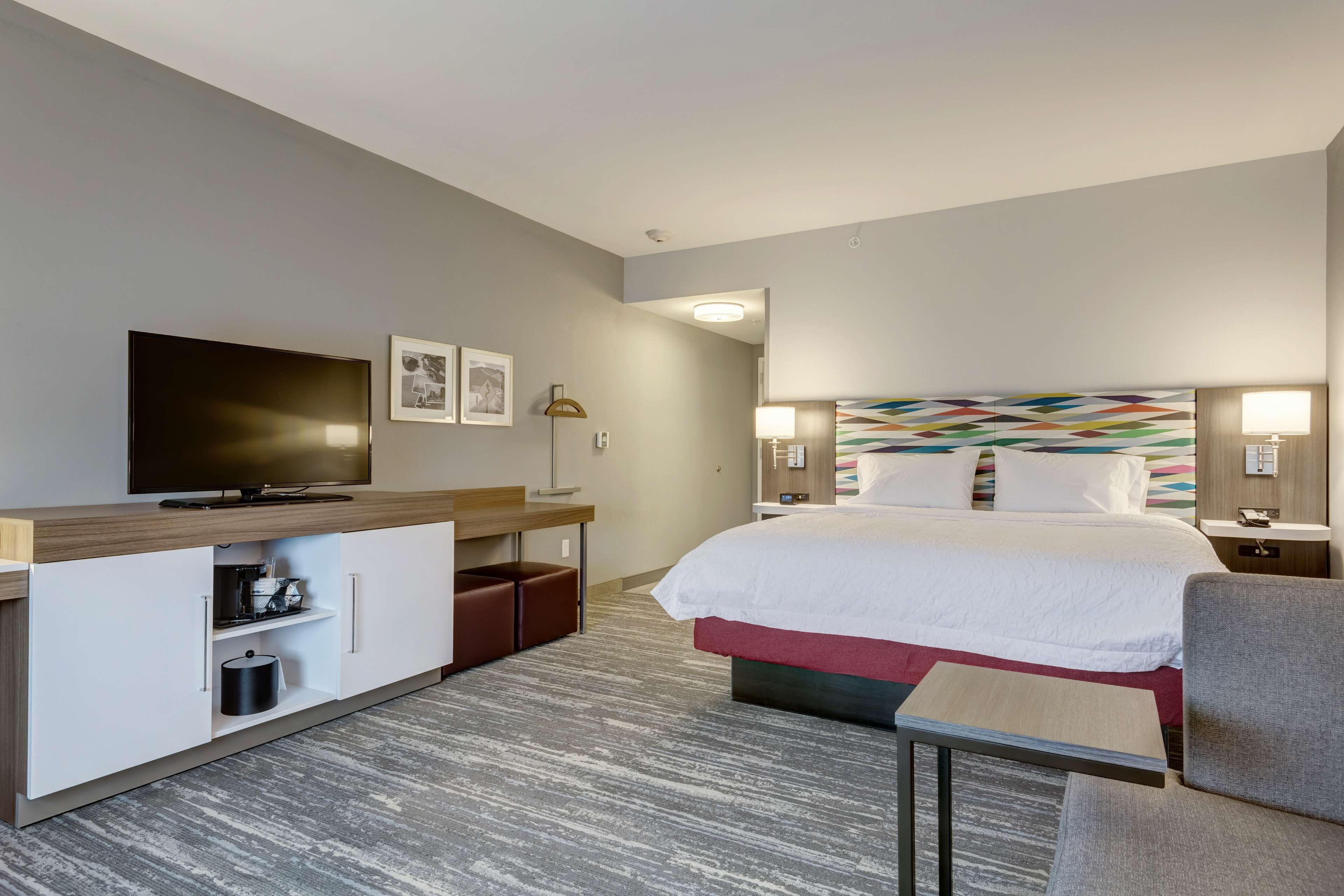 A hotel room with a bed, a TV, a desk, and a chair.
