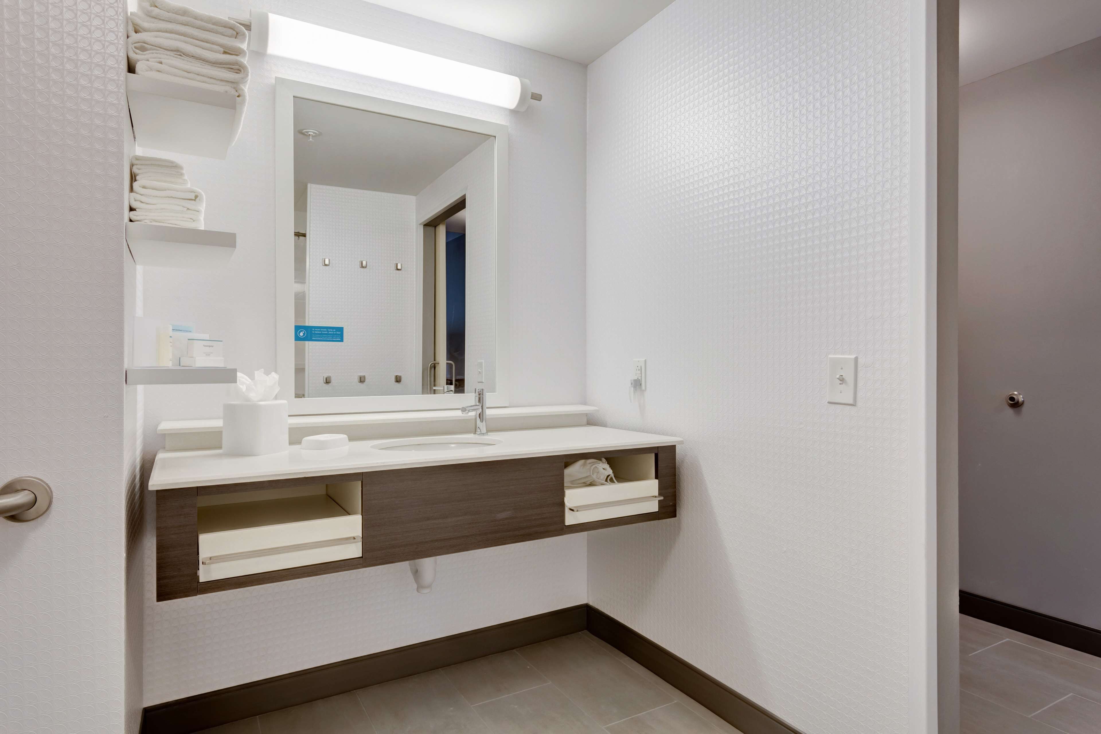 A modern bathroom with a white vanity, a mirror, and a towel rack.