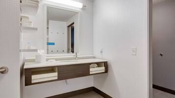 A modern bathroom with a white vanity, a mirror, and a towel rack.