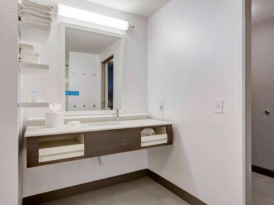 A modern bathroom with a white vanity, a mirror, and a towel rack.