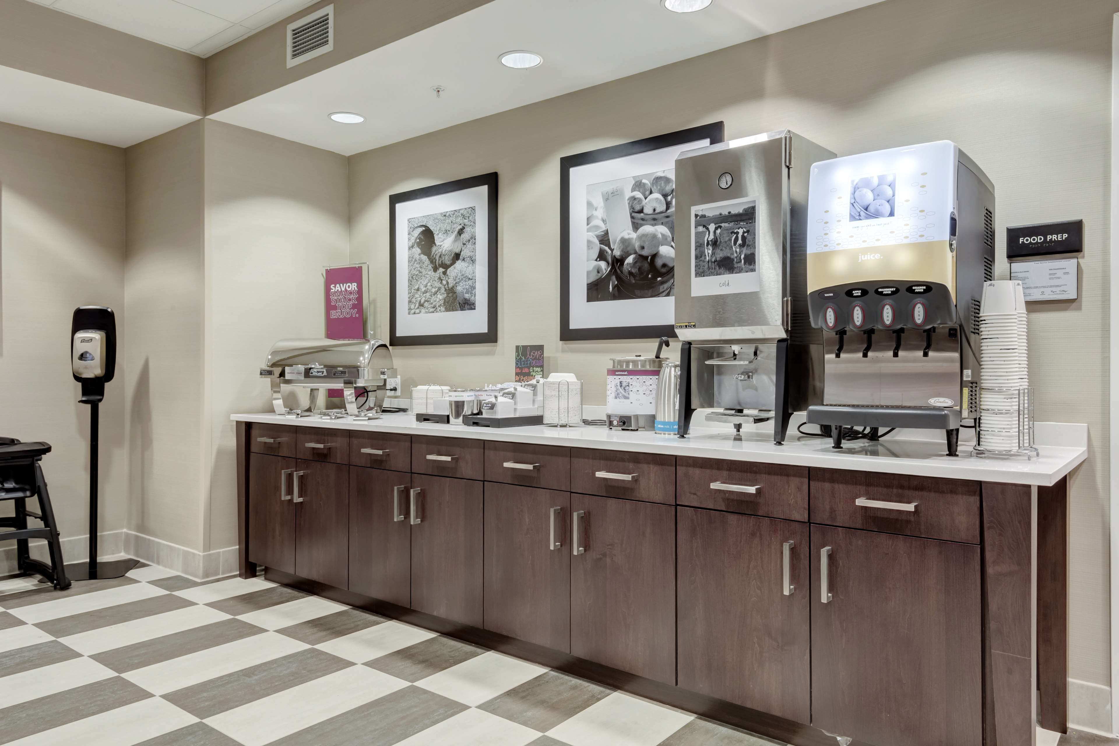 A self-service coffee station with a juice dispenser and a food prep area in a hotel lobby.