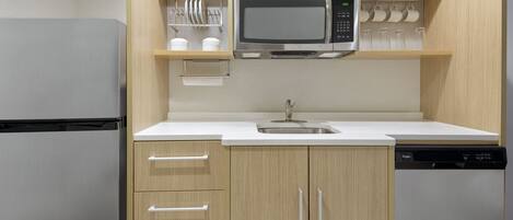 A compact kitchen with a built-in microwave, a sink, and a dishwasher.